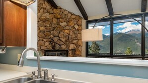 Eine Küche mit Steinwand, einem großen Fenster und Bergblick sowie einem modernen Wasserhahn.