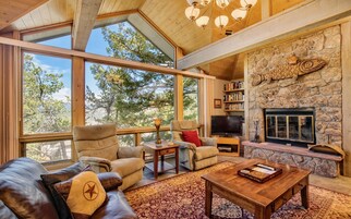 Un salón amplio con ventanas grandes, una chimenea de piedra y un rincón de estar acogedor.