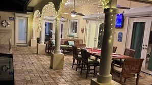 An outdoor dining area with brick flooring, wooden tables and chairs, and decorative lighting. - Villagoona, waterfront, infinity pool, dir.access to the Gulf of America (Cape Coral)
