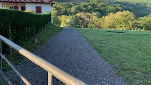 A gravel path leading to a building with a red door and a white wall.
