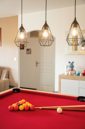 A pool table with billiard balls and a cue stick, a red pool table cloth, and three hanging pendant lights with exposed bulbs. - farm house at the foot of the mountains and 1 kilometer from Espelette center (Espelette)
