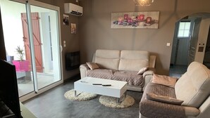 A modern living room with a beige sofa, a white coffee table, and a flat-screen TV.