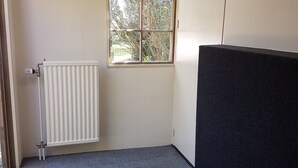 A room with a radiator, a window with a view of trees, and a dark-colored partition. - Attractive detached house with all amenities and garden / terrace, lots of privacy! (Amerongen)