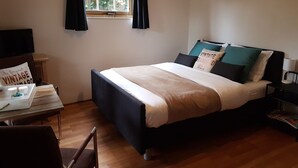 A bedroom with a bed, a window with curtains, a bedside table, a chair, and a wall-mounted TV. - Attractive detached house with all amenities and garden / terrace, lots of privacy! (Amerongen)