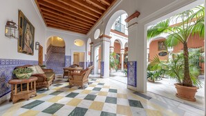 A spacious lobby with checkered flooring, wicker furniture, and potted plants.