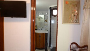 A bathroom with a wooden cabinet, a mirror, and a framed painting on the wall. - Wacos House in the heart of Varadero (Varadero)