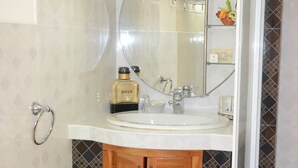 A bathroom with a round mirror, a sink, and a wooden cabinet. - Wacos House in the heart of Varadero (Varadero)