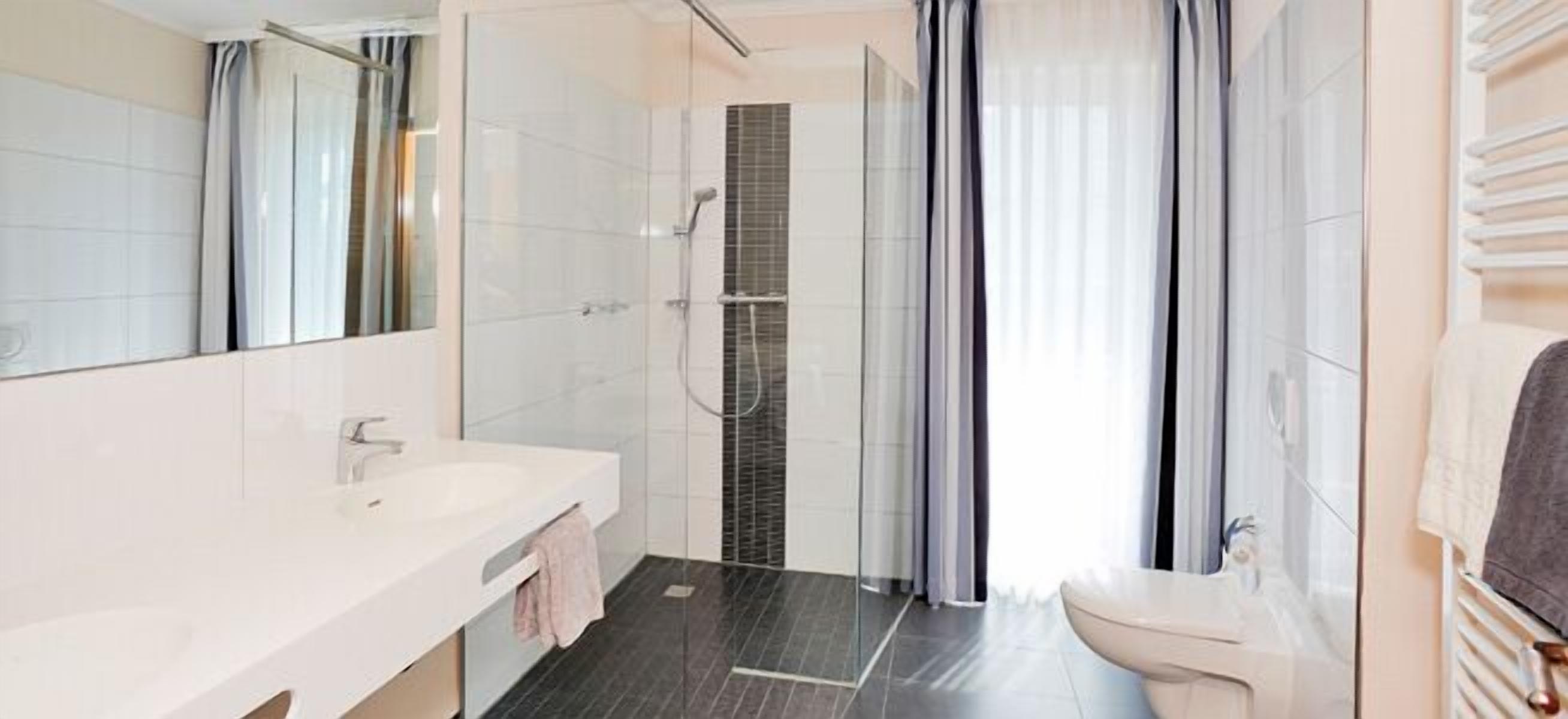 Une salle de bain moderne avec une douche à parois de verre, un lavabo blanc et des toilettes.