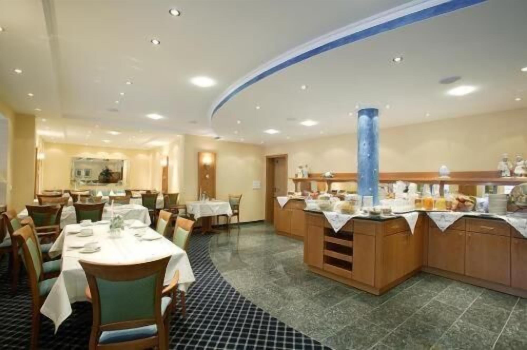 Une salle à manger d’hôtel avec des tables rondes, des chaises et un buffet.