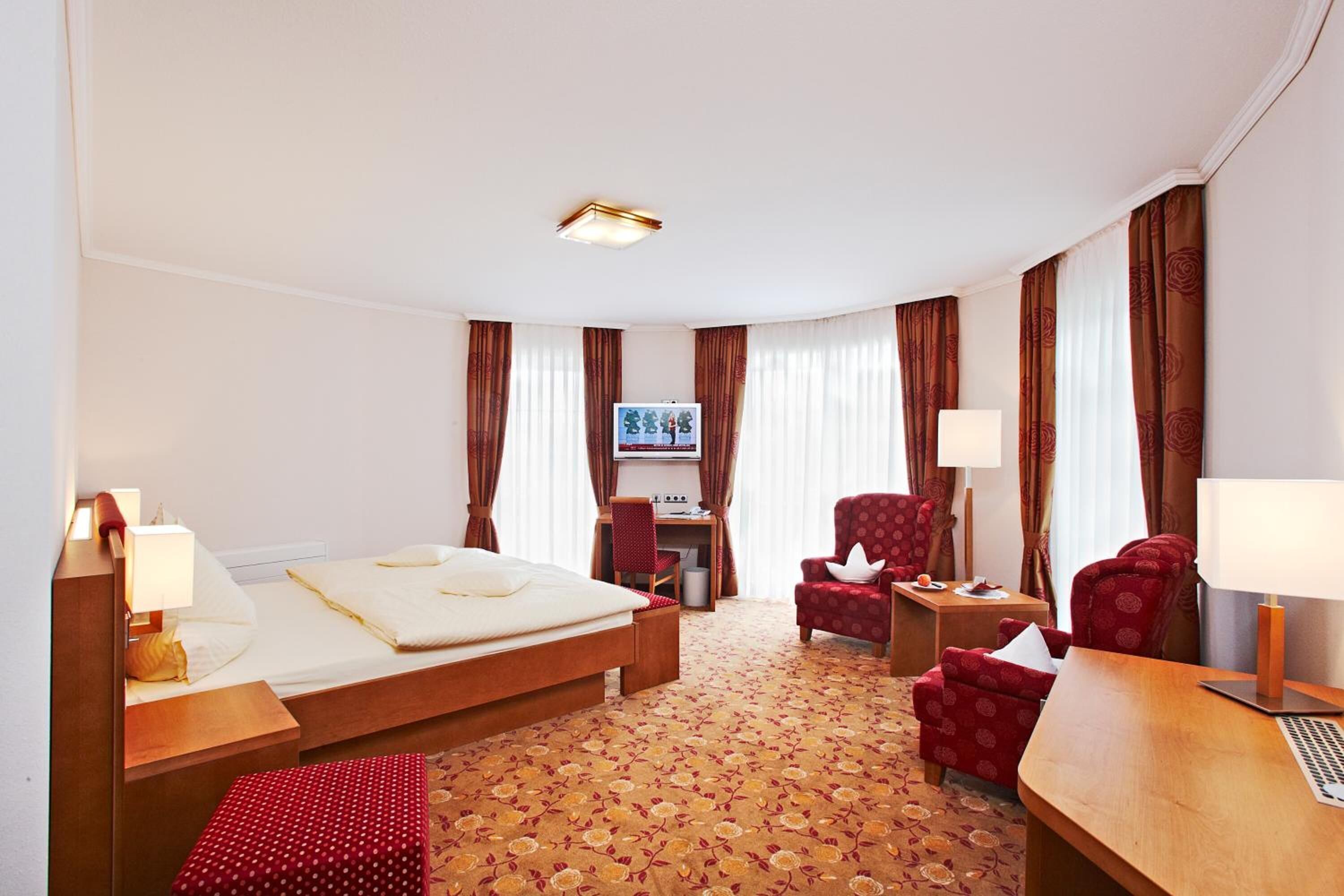 A hotel room with a bed, desk, chair, and a TV.