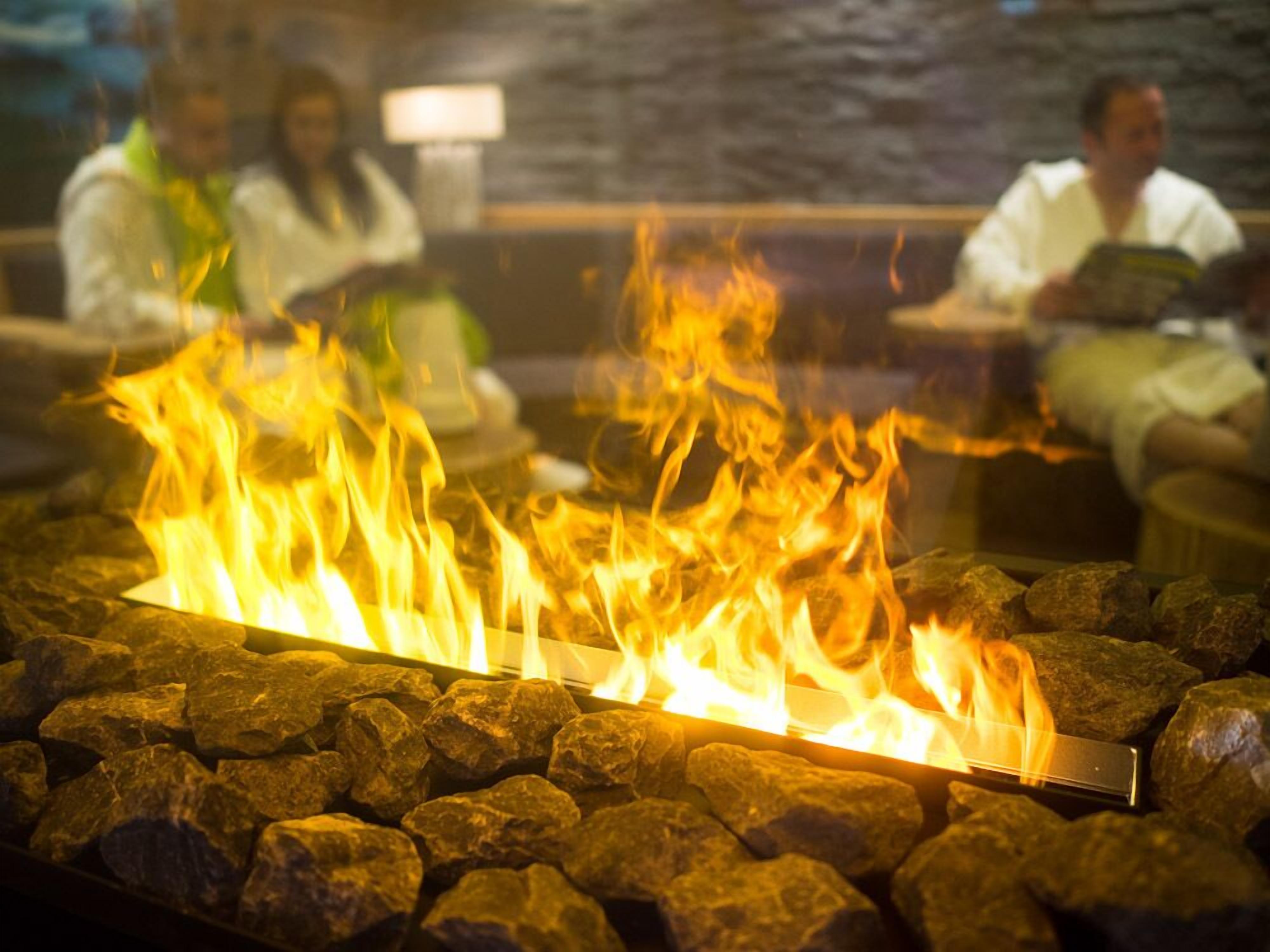 A fire feature surrounded by rocks, with people seated in the background.