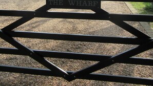 Une entrée fermée par un portail, sur laquelle est apposée une plaque indiquant : « THE WHARF ».