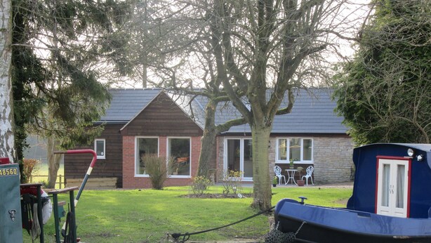 Une maison avec une façade en briques, une pelouse et un petit jardin.