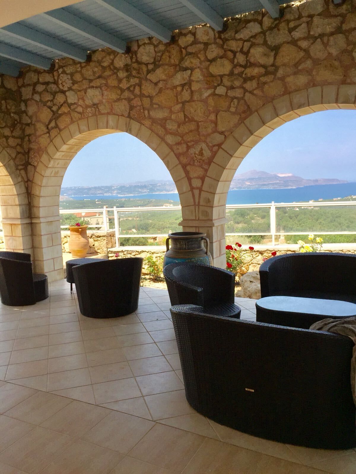Un espace extérieur abrité, doté d'arches en pierre, de mobilier en osier et offrant une vue sur le paysage.