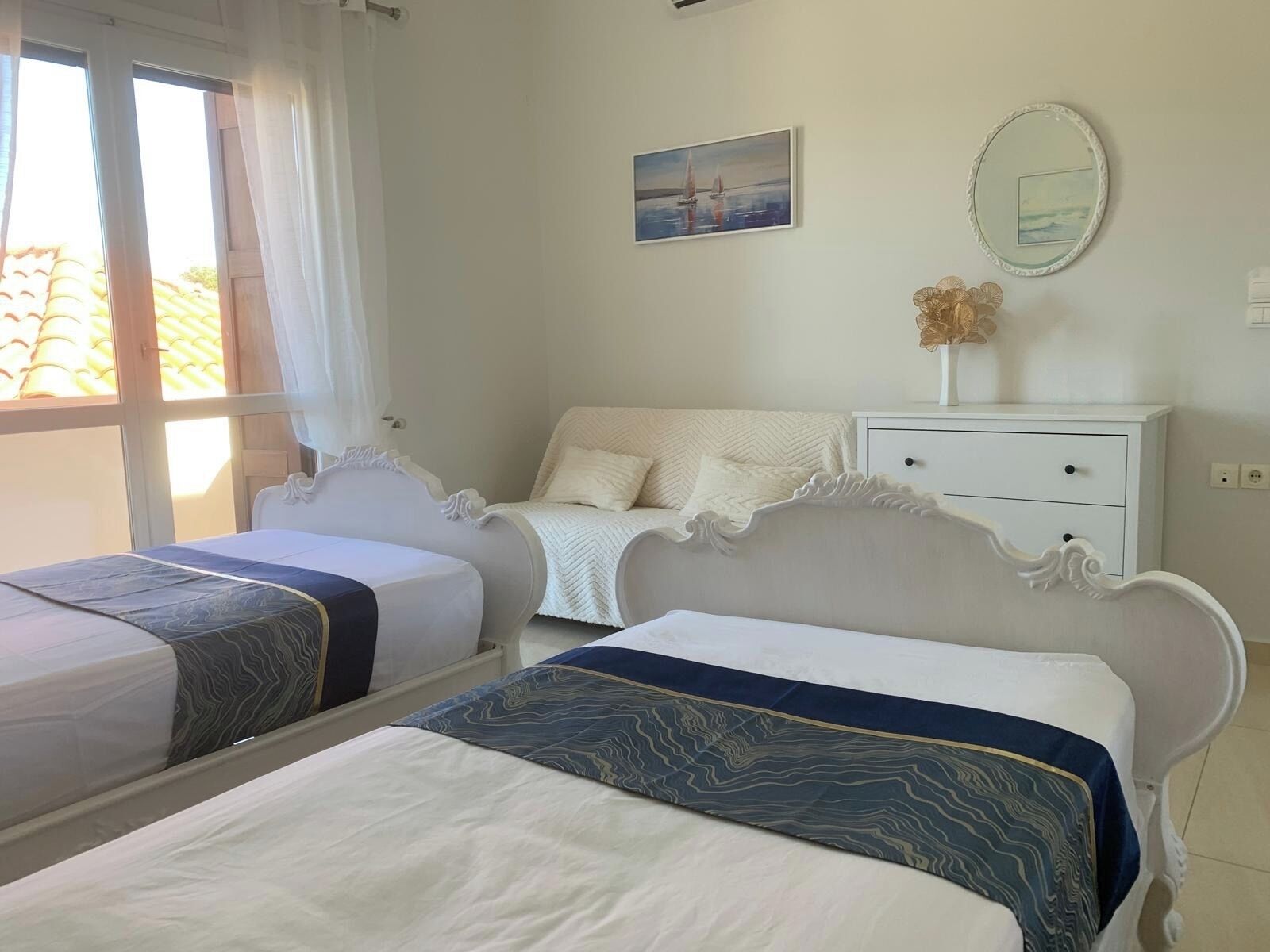 Ein Schlafzimmer mit zwei Betten, einer weißen Kommode, einem Spiegel und einem Bild an der Wand.