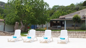 A poolside area with white lounge chairs and a stone wall.