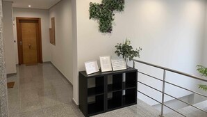 Ein moderner Flur mit einer Holztür, einem schwarzen Konsolentisch mit gerahmten Dokumenten und einer grünen Wanddekoration.