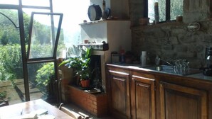 Una cocina con armarios de madera, encimera de ladrillo y ventana con vistas a follaje.