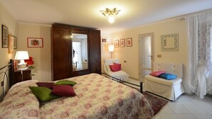 Un dormitorio con una cama grande, mesitas de noche, una silla y un espejo.
