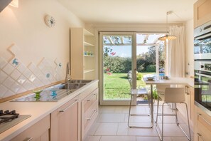Een moderne keuken met een groot raam, een eethoek en uitzicht op een tuin.