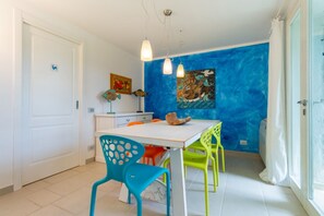 Un coin repas avec une table blanche, des chaises colorées et un mur d’accent bleu.