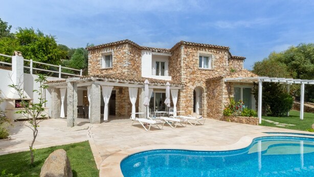 A stone house with a swimming pool and outdoor seating.