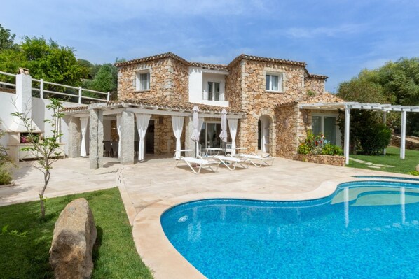 Une maison en pierre avec une piscine et un espace extérieur aménagé pour se détendre.
