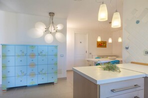 Eine Küche mit einem blauen Schrank, einer weißen Arbeitsplatte und Pendelleuchten.
