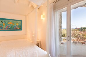 Une chambre à coucher comprenant un lit, un tableau accroché au mur, une table de chevet et une fenêtre donnant sur l’extérieur.
