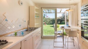 Eine moderne Küche mit großem Fenster, einem Essbereich und Blick auf einen Garten.