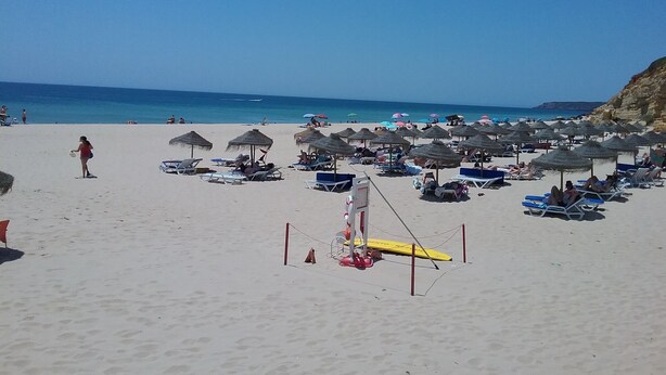 A beach with sun loungers and umbrellas, a lifeguard stand, and a clear view of the ocean. - Large villa - 6 rooms, garden and swimming pool in Budens, near Salema beach.  (Budens)