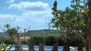 A patio area with a fire pit, lounge chairs, and a pool in the background. - Large villa - 6 rooms, garden and swimming pool in Budens, near Salema beach.  (Budens)