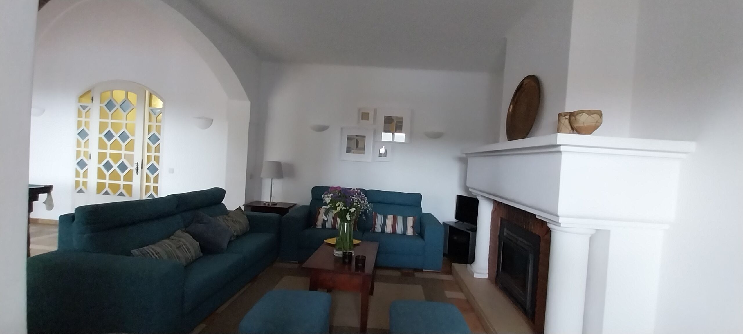 A living room with a fireplace, two sofas, a coffee table, and a decorative vase.