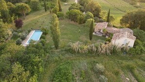 Une villa avec piscine, entourée d’une végétation luxuriante et de vignobles.