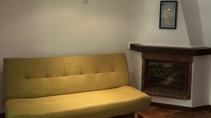 Un salon avec un canapé, une cheminée et une lucarne.