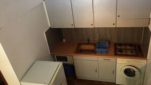 Une cuisine compacte équipée d’un évier, d’une cuisinière et d’un lave-linge.