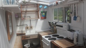 A compact kitchen with a stove, toaster, and wooden countertop.