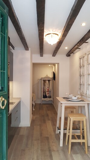 Una stanza con soffitto in legno, un lampadario, un tavolo con degli sgabelli e uno specchio appeso al muro.