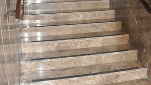 Un escalier en marbre, doté de rampes, mène à une porte surmontée d’une œuvre d ’art encadrée.