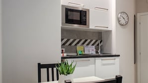 A compact kitchen with a microwave, a clock, and a small countertop with a plant. - Interior 1 Ciampino Rome with private balcony (CIAMPINO)
