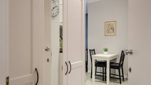 A dining area with a white table and black chairs, a clock on the wall, and a framed picture above the table. - Interior 1 Ciampino Rome with private balcony (CIAMPINO)