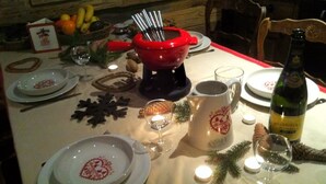 A dining table set with plates, cutlery, a red hot pot, a bottle of wine, and candles. - Beautiful 4* flat in a chalet with shared sauna, 300 meters from the slopes   (Les Avanchers-Valmorel)