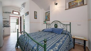 Een slaapkamer met een bed, een tafeltje en een schilderij aan de muur.