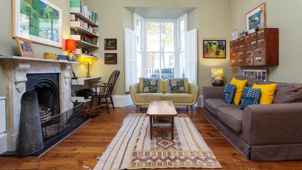 A cozy living room with a fireplace, a sofa, a coffee table, and a bookshelf. - East London Elegance, by Veeve (London)