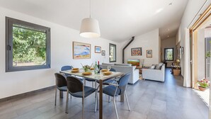 Un espace repas moderne avec une table en verre, des chaises bleues et un canapé gris en arrière-plan.