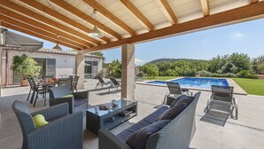 Une terrasse extérieure aménagée avec des meubles en osier, une piscine et une vue sur le paysage environnant.