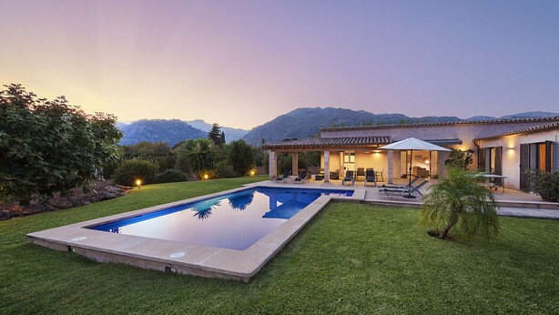 Une maison moderne dotée d’une piscine, d’un espace extérieur aménagé et offrant une vue sur les montagnes.