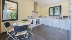 Une cuisine moderne avec des armoires blanches, un four en acier inoxydable, un four à micro-ondes et une grande fenêtre donnant sur un paysage verdoyant.