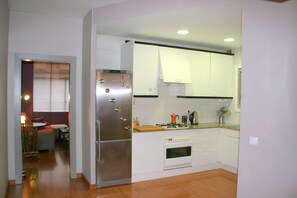 A compact kitchen with white cabinets, a stainless steel refrigerator, a gas stove, and a small countertop. - SWEET APARTMENT IN GRACE DISTRICT! (Barcelona)