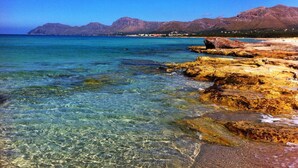 A coastal landscape with clear water, rocky shore, and distant mountains. - Luxury house on the front line of the sea (Son Serra de Marina)